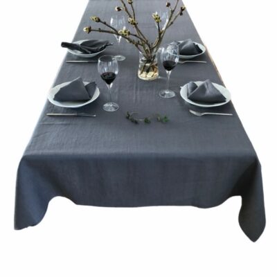 Her vises et dækket bord med en grå hørdug og grå hørservietter fra ecoinvent. På midten af bordet står en buket blomster.
